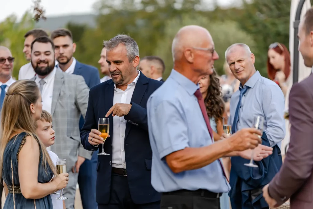 A ceremóniamester az esküvői koccintás pillanataiban beszélget a vendégekkel. Bagi Péter – ceremóniamester