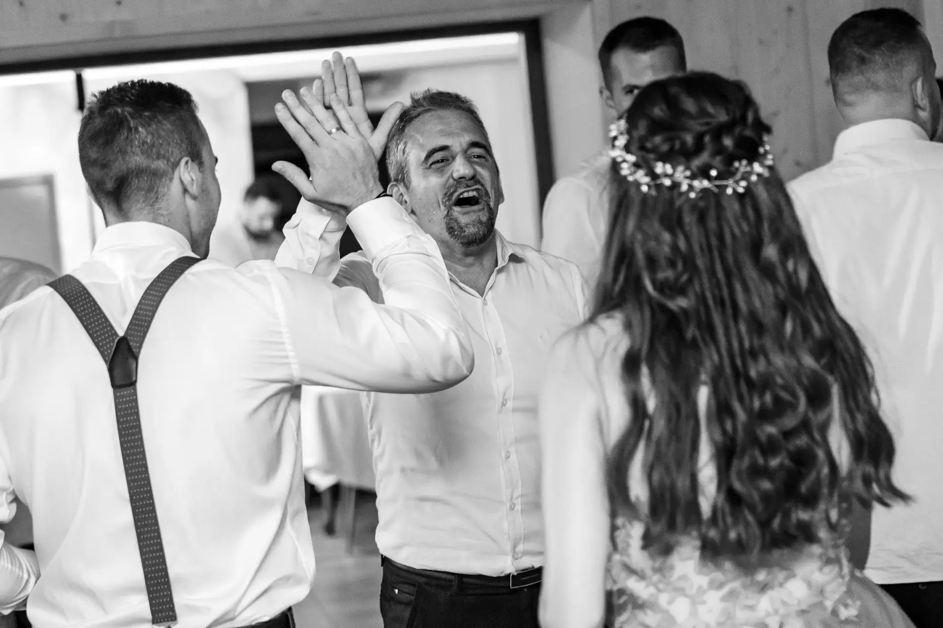 Fekete-fehér pillanat az esküvőről, a ceremóniamester vidáman pacsizik a vendégekkel. Bagi Péter – ceremóniamester