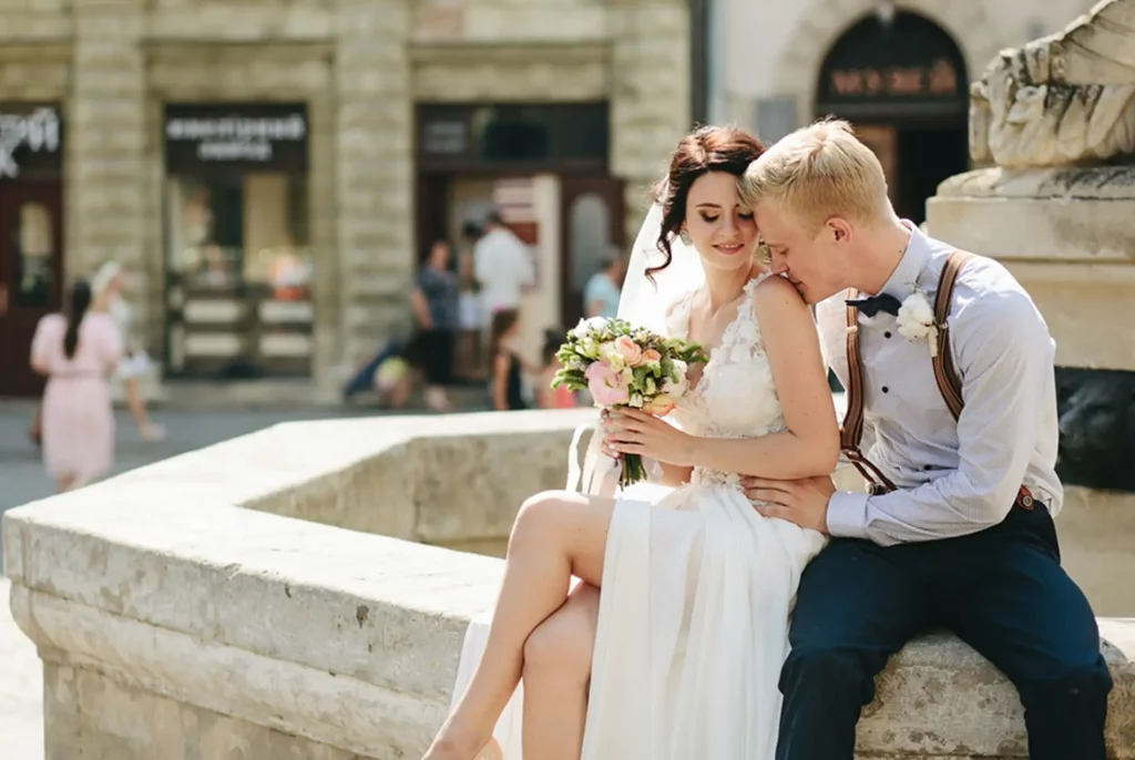 Az ifjú pár romantikus pillanatot oszt meg egy városi esküvő helyszínén, miközben a ceremóniamester gondoskodik a háttérben a gördülékeny szervezésről. Bagi Péter – ceremóniamester